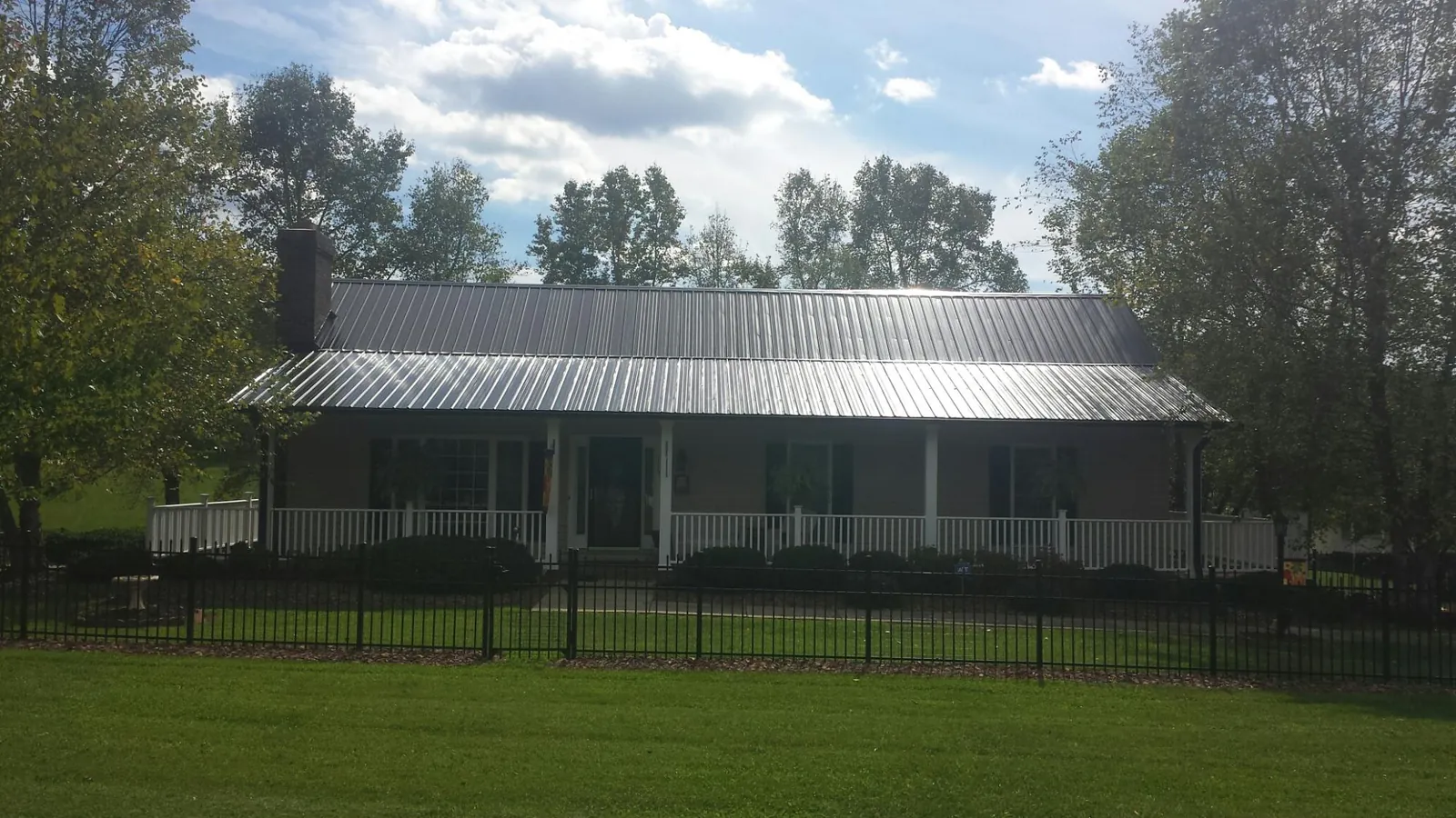 Gray metal roof on a brick ranch with a full width front porch — Gutter Guard Installation work by our crew in Lefor