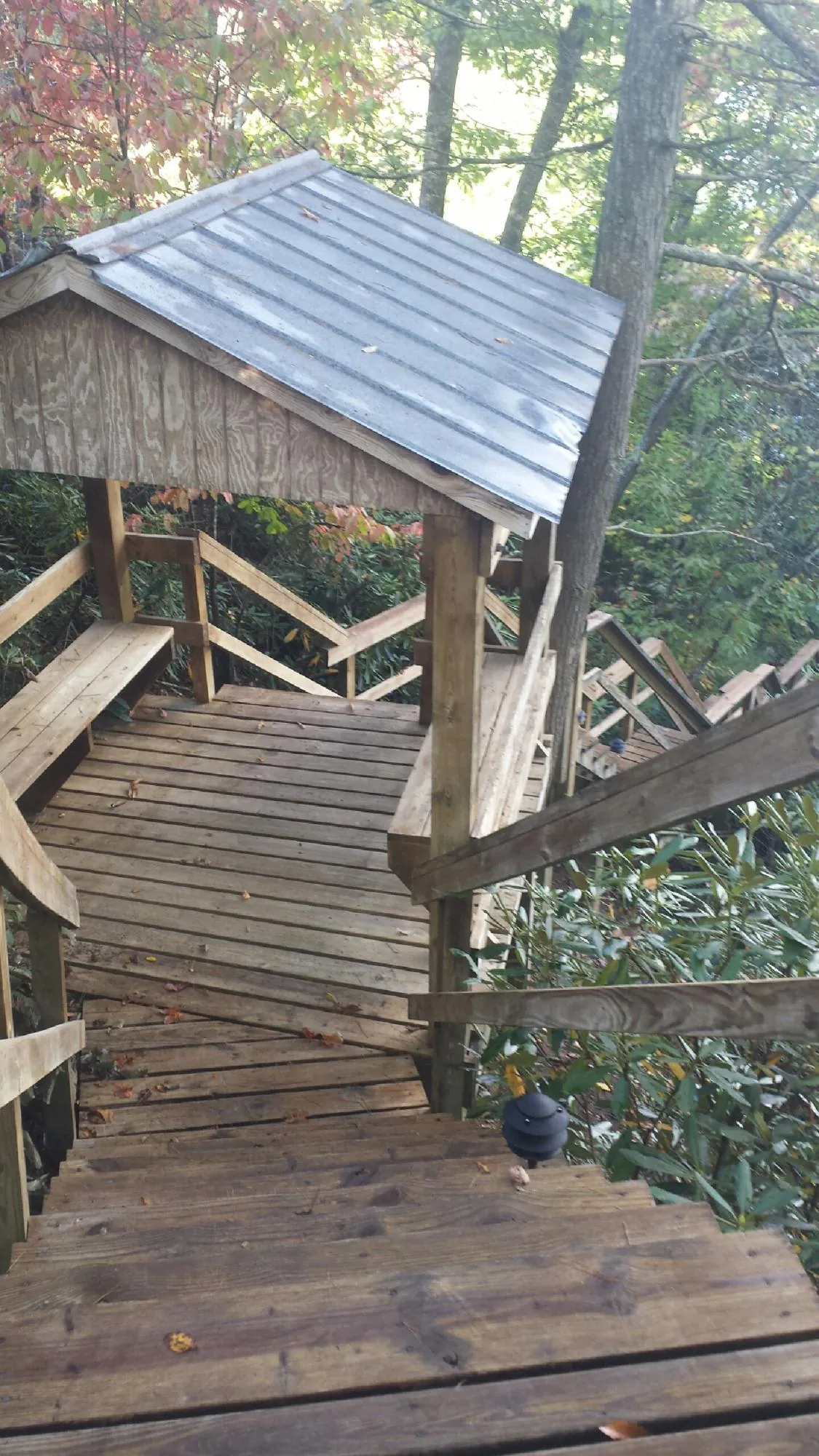 Metal roofed shelter over wooden steps on a wooded walkway — Skylight Repair & Installation work by our crew in Lefor