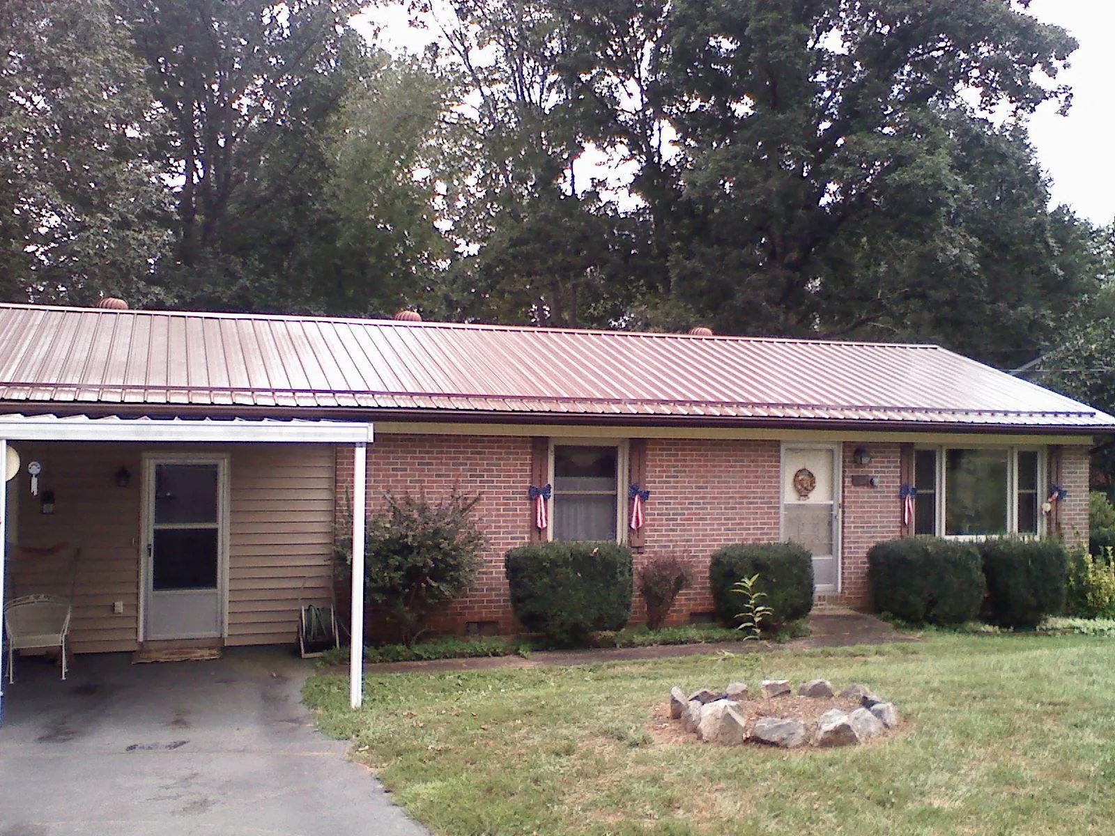 Bronze metal roof and carport on a brick ranch home — Roof Repair work by our crew in Lefor